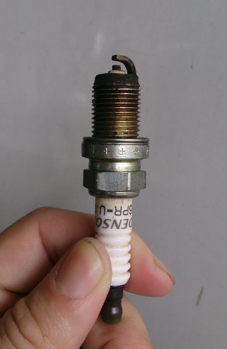 Bujía de encendido: aislante, cuerpo y electrodos visibles..