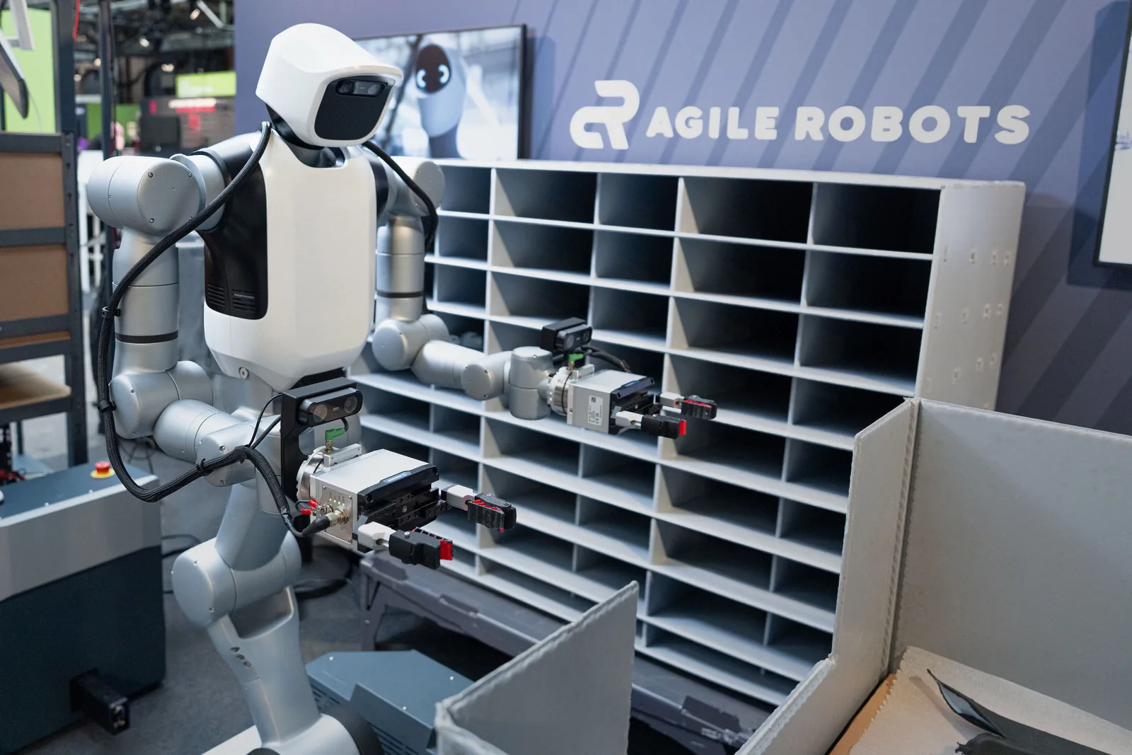 Robot móvil de Agile Robots con dos brazos ante contenedores y estanterías de secuenciación.