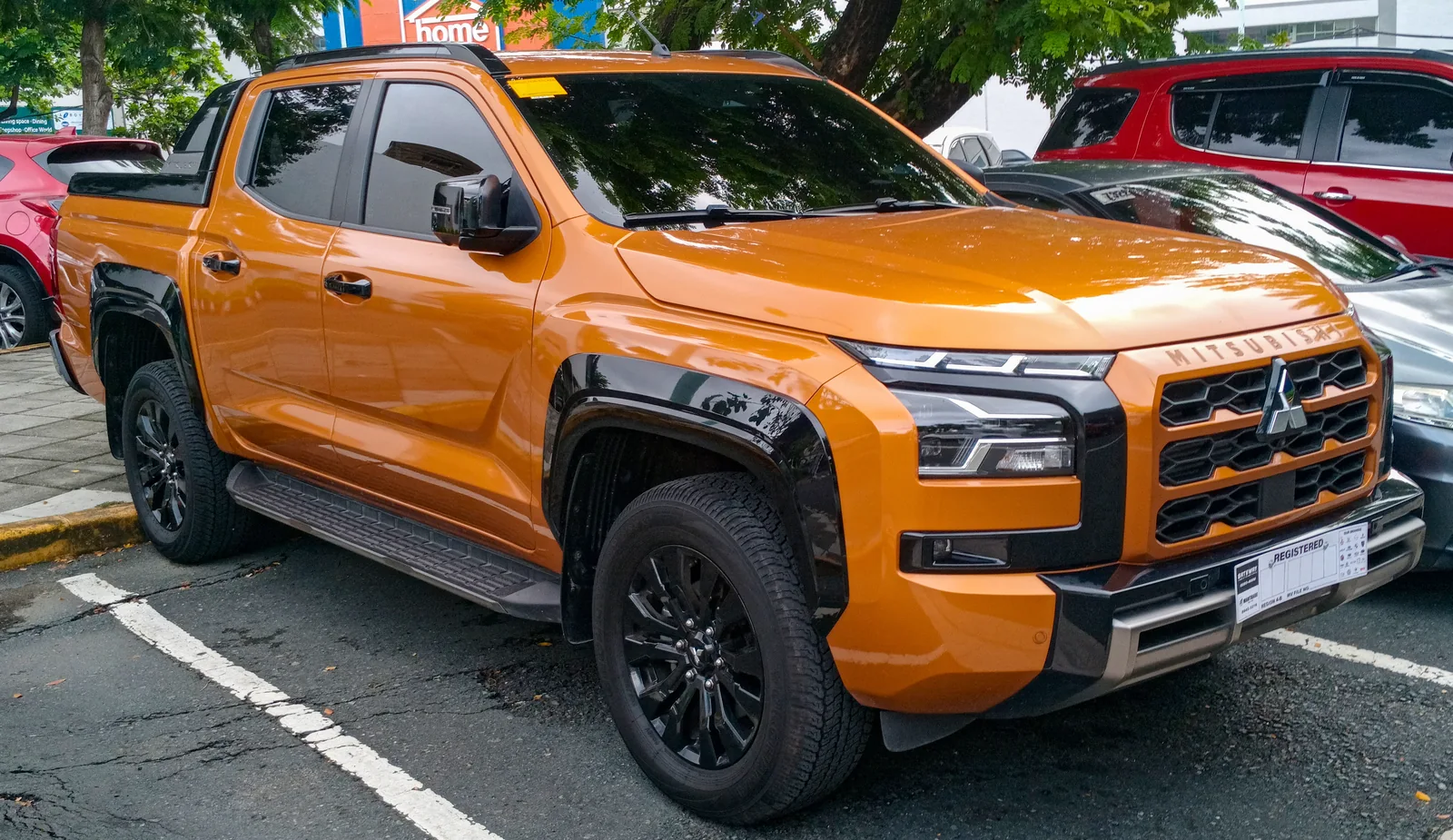Mitsubishi Triton Athlete naranja de 2024 aparcado, visto de tres cuartos delantero.